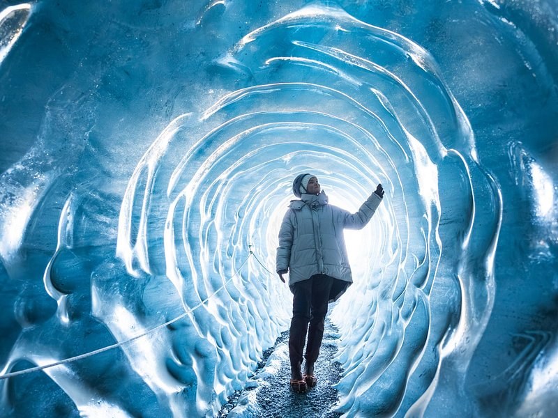 A visitor seen from behind in a ringed blue ice tunnel